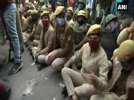 Police personnel sit on road in Nangloi to block farmers' tractor rally